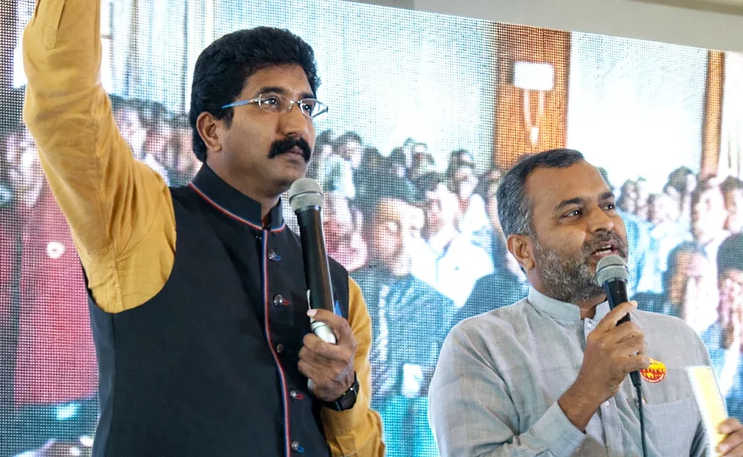 Two speakers holding microphones on a stage.