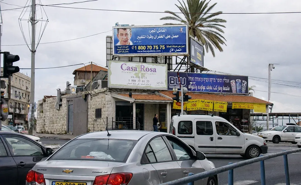 Large blue campaign billboard above a street corner in Bethlehem, West Bank