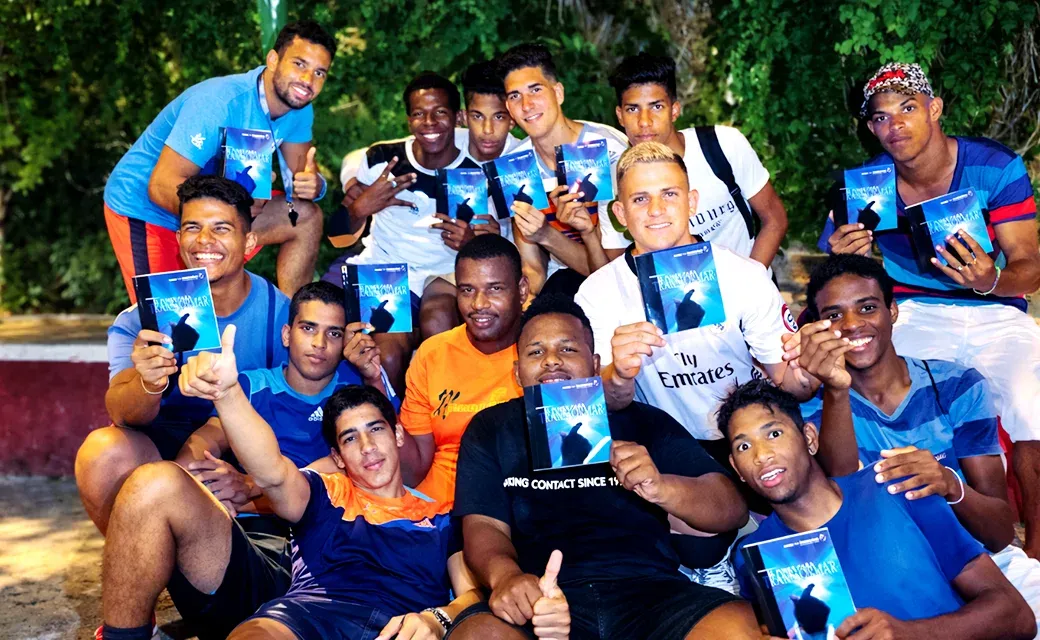 Group of young men holding campaign books outdoors at night.