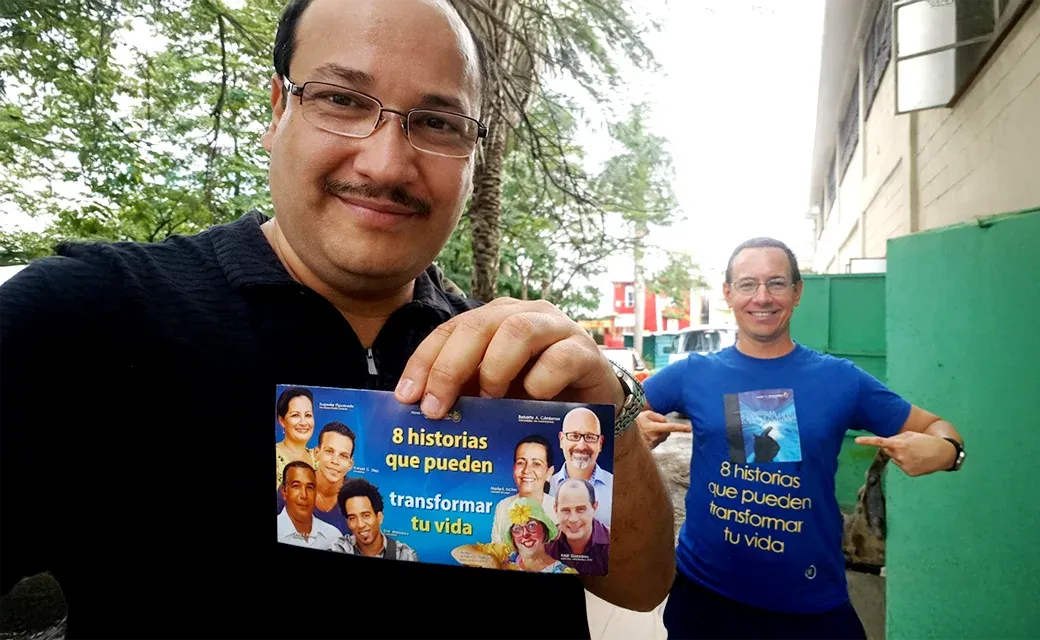 Two men holding and wearing a Spanish campaign booklet design.
