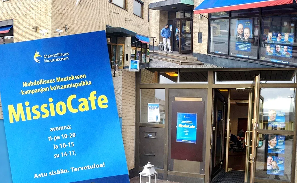 A building entrance with campaign posters and a sign for a campaign meeting point in Finland.