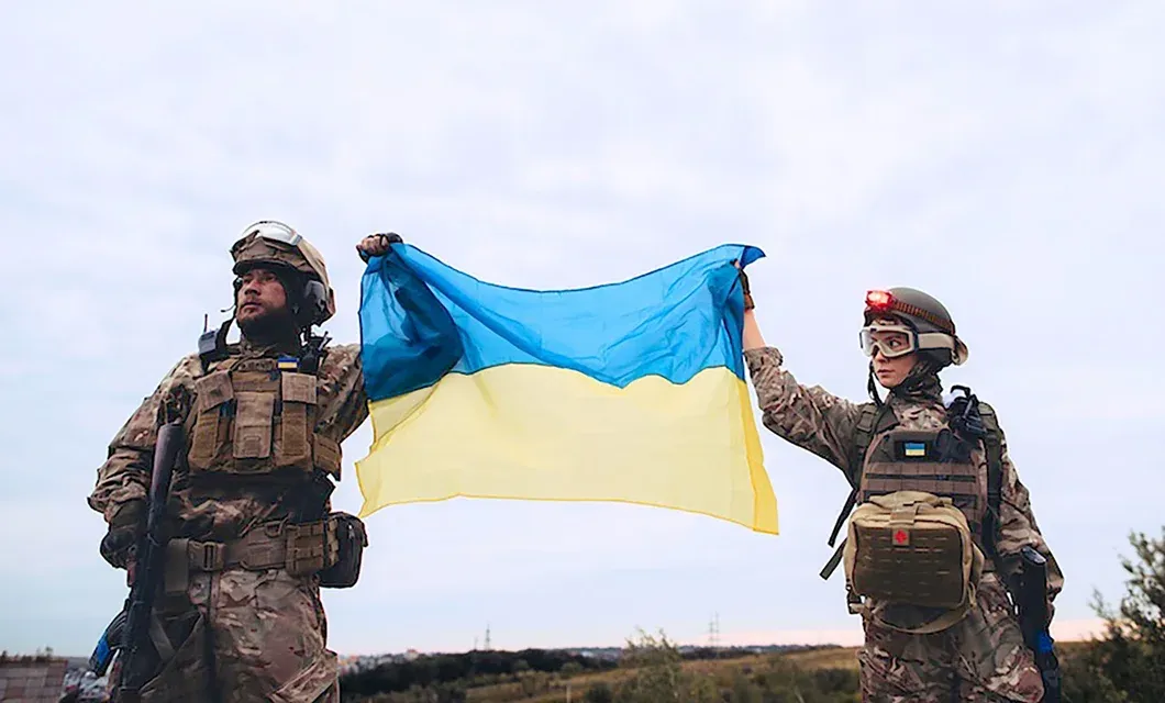 Ukrainian soldiers hold a large Ukrainian flag outdoors.