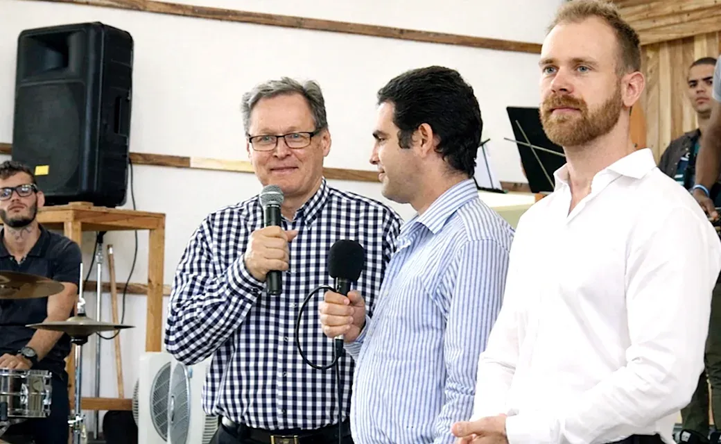 Three men at church, two holding microphones.